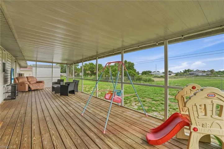 Expansive screened-in porch featuring a wood-finish floor, a solid roof overhead, and open-air screening