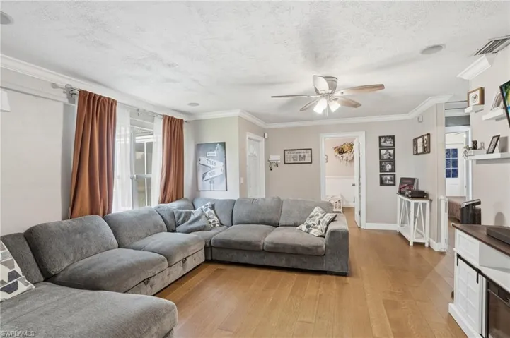 Living area featuring wood-finish flooring, crown molding, a ceiling fan, and recessed lighting