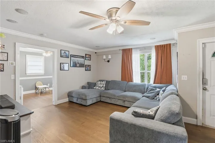 Spacious room featuring wood-finish flooring, a ceiling fan with integrated lighting, recessed lighting, and crown molding