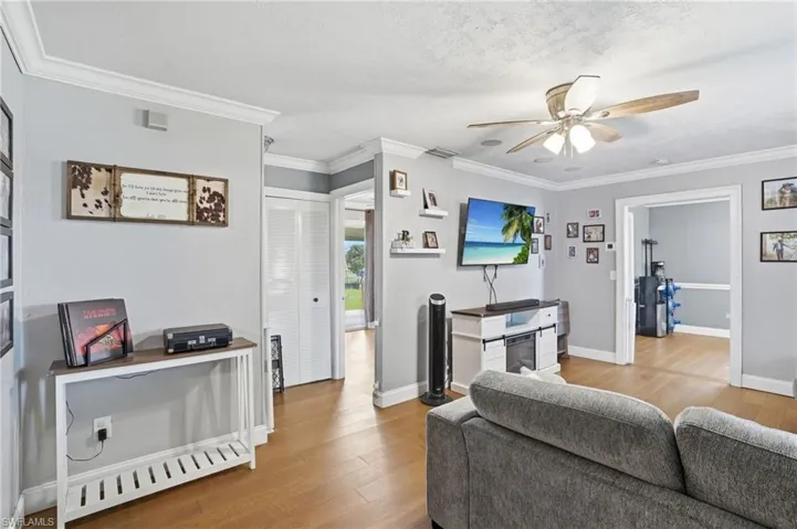 Bright living area featuring wood-finish flooring, light gray wall paint, and white crown molding
