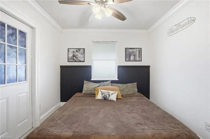 Compact room featuring a multi-pane door, a single window, and a ceiling fan with integrated lighting