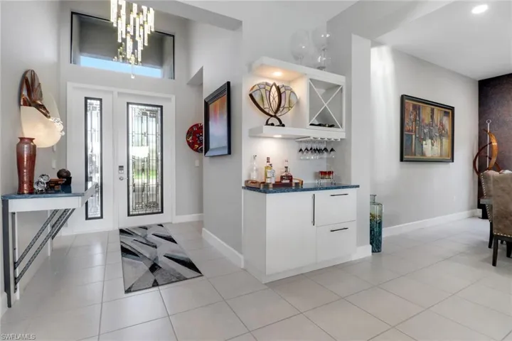 Welcoming entryway showcasing a stunning  light fixture, built-in table, and custom dry bar