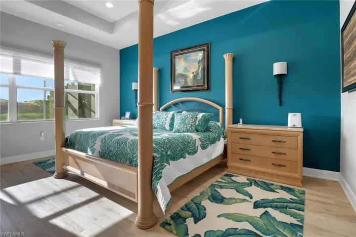 Spacious primary bedroom with tray ceiling, ceiling fan, and peaceful lake views
