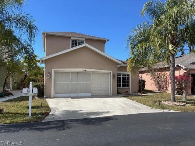 View of front facade with stucco siding, driveway, a front yard, and an attached garage