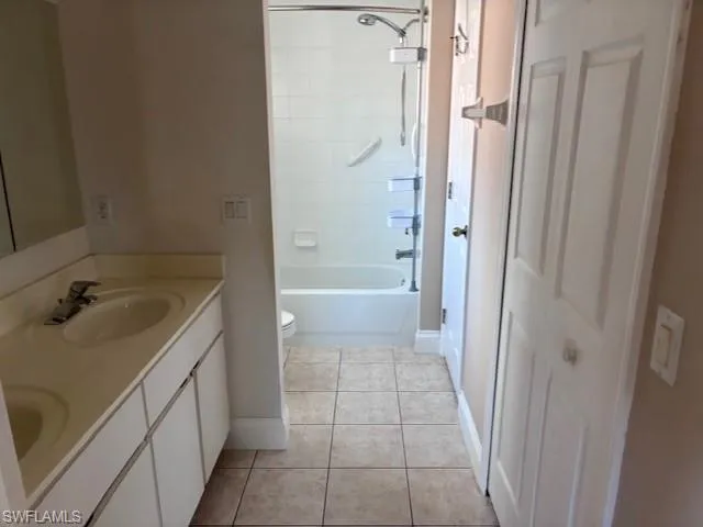 Bathroom with double vanity, shower / bathtub combination, and light tile patterned floors