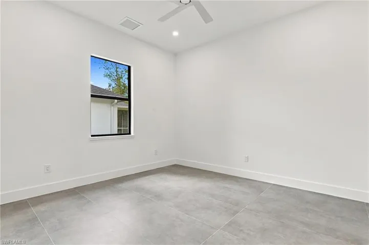 Neutral-toned oversized floor tile, matte black ceiling fan, and window with black frame