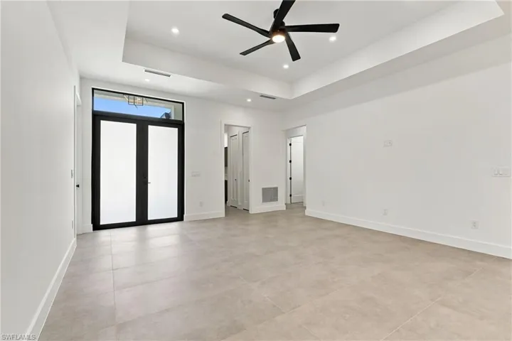 Tray ceilings with recessed lighting, large-format tile flooring, contemporary kitchen cabinetry, waterfall-edge island, and modern linear pendant lighting