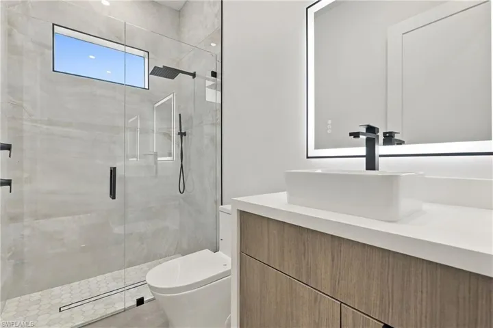 Spacious garage featuring a finished epoxy floor, white interior walls, two framed windows, and a glass-paneled entry door