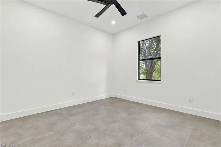 Interior space featuring large-format ceramic tile flooring, neutral wall finishes, recessed lighting, and a matte black ceiling fan