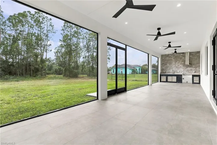 Covered lanai featuring large-format ceramic tile flooring, recessed lighting, and three matte black ceiling fans, framed by floor-to-ceiling windows and metal-framed screening