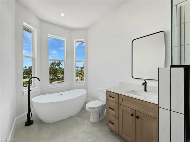 Bathroom 2 featuring vanity, a freestanding tub, light tile patterned flooring, and recessed lighting