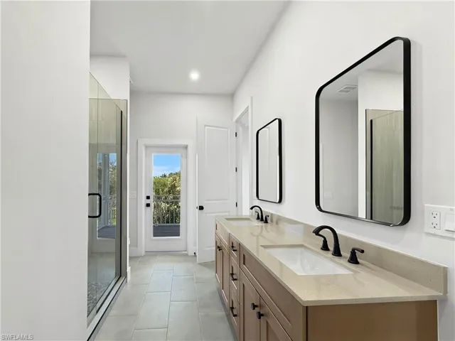 Primary Bathroom featuring double vanity, a stall shower, light tile patterned flooring, and recessed lighting