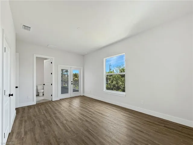 Primary Bedroom featuring ensuite bathroom and French doors to outside deck