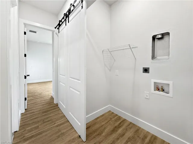 Laundry room featuring a barn door, hookup for full-size stackable washer/dryer and storage