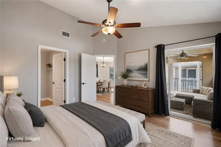 Vaulted ceiling with a ceiling fan, wood-finish flooring, sliding glass door leading to an outdoor space, built-in shelving, and a double-panel door with black hardware