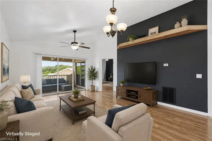 Vaulted ceilings with a ceiling fan, wood-finish flooring, and a sliding glass door leading to a balcony