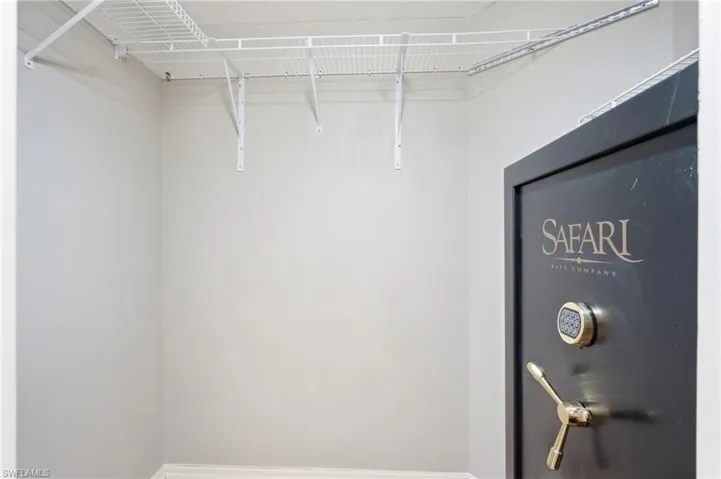 White wire shelving system with wall-mounted brackets and a large safe with a safe with combination lock and brass handle