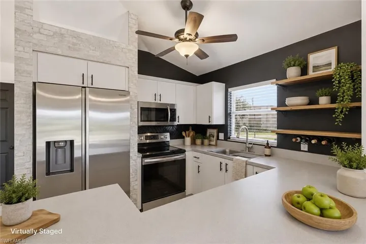 Stainless steel appliance suite, white cabinetry, dark subway tile backsplash, light countertops, and built-in shelving