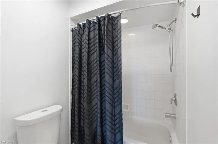 Recessed lighting, tile shower surround, bathtub, and chrome fixtures