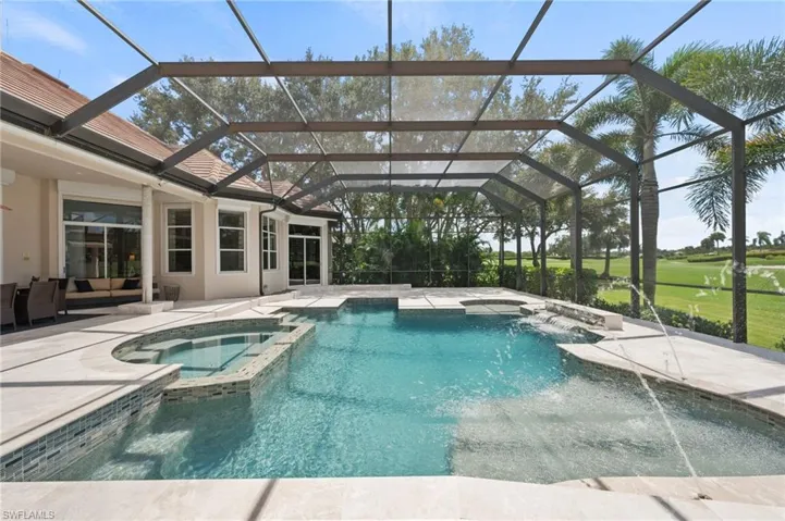 View of pool with a pool with connected hot tub, a sunroom, a patio, glass enclosure, and view of golf course