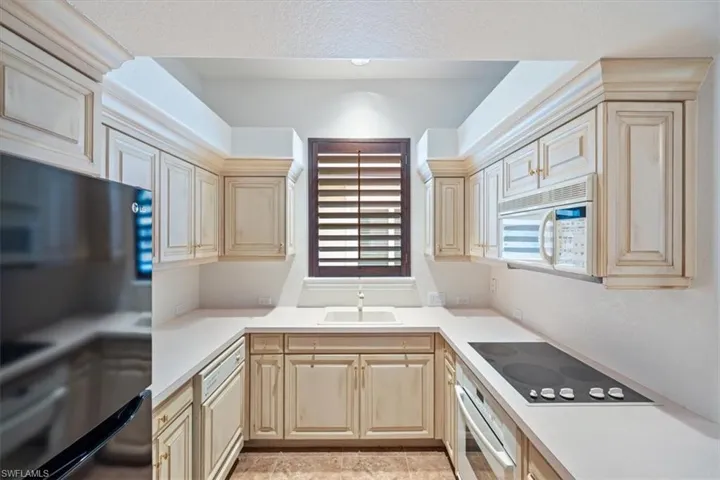 Kitchen featuring black appliances, light countertops, light brown cabinets, and light tile patterned floors