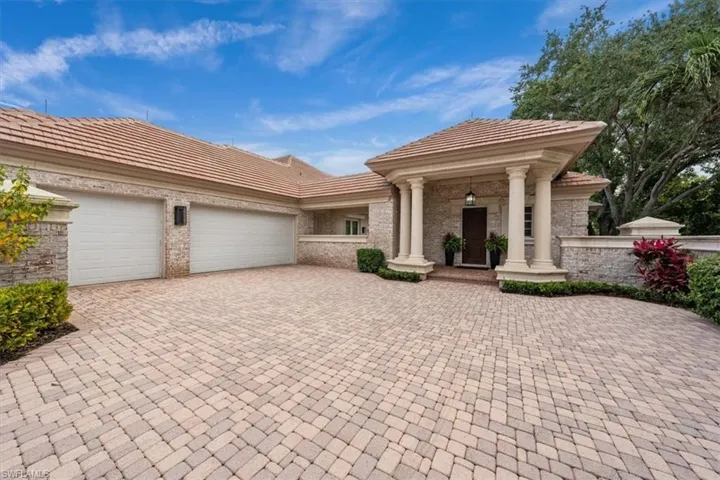 View of front facade with decorative driveway, an attached garage, a porch, a tile roof, and brick siding