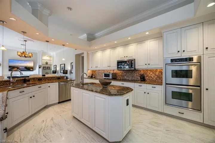 Kitchen with ornamental molding, recessed lighting, white cabinets, appliances with stainless steel finishes, and light marble finish flooring