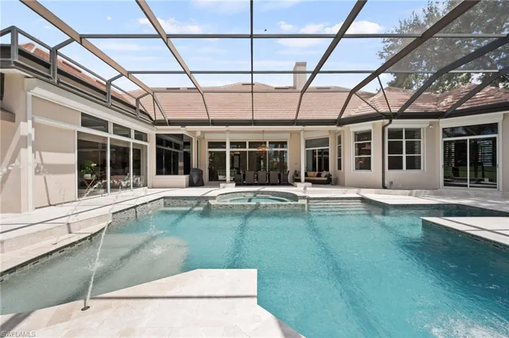 View of pool with glass enclosure, a sunroom, a pool with connected hot tub, and a patio