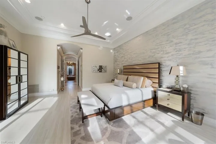 Bedroom with an accent wall, arched walkways, light wood-style floors, a ceiling fan, and recessed lighting