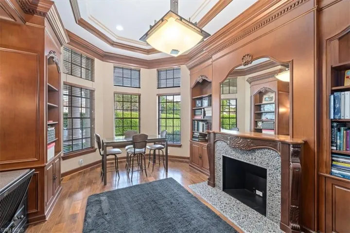 Living area featuring crown molding, healthy amount of natural light, light wood-type flooring, a high end fireplace, and built in shelves