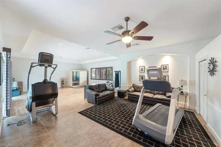 Workout room featuring a raised ceiling and a ceiling fan