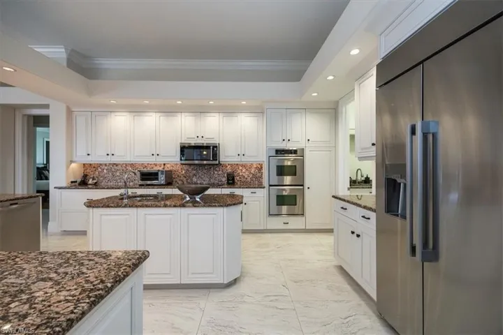 Kitchen featuring stainless steel appliances, recessed lighting, white cabinets, dark stone countertops, and decorative backsplash