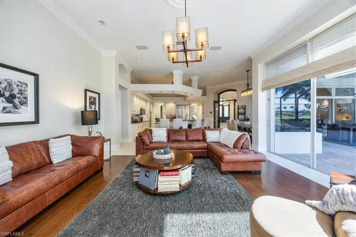 Living room featuring crown molding, wood finished floors, and a chandelier