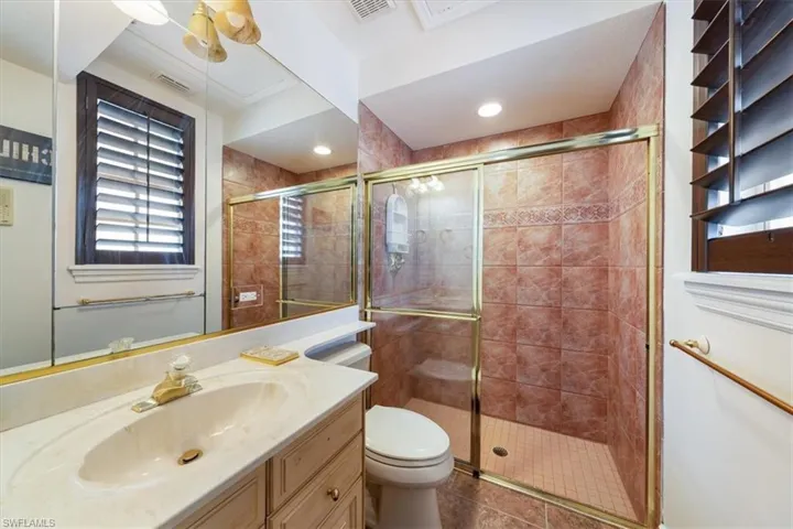 Full bath with vanity, a stall shower, and dark tile patterned flooring