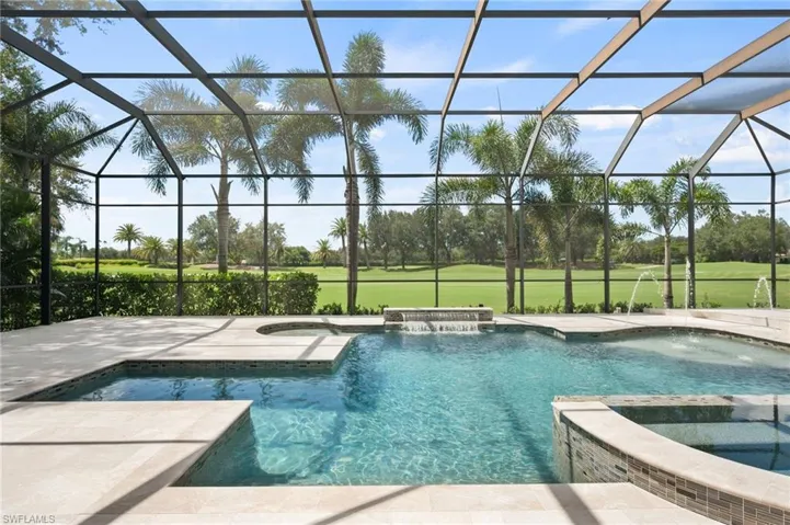 View of pool featuring a pool with connected hot tub, glass enclosure, a sunroom, a patio area, and golf course view