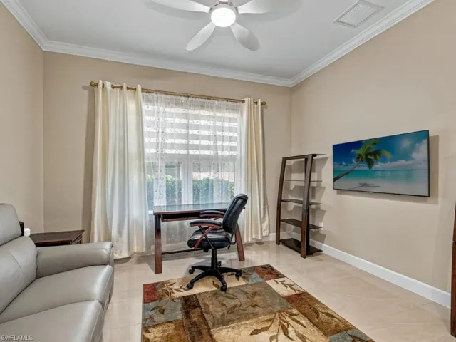 Neutral-toned interior room featuring crown molding, polished tile flooring, and a multi-blade ceiling fan