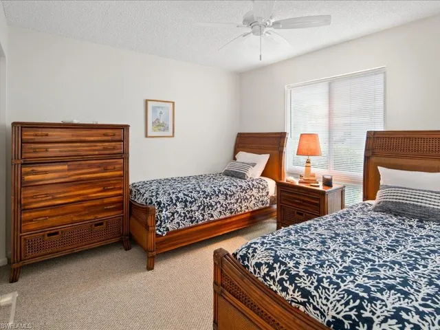 Guest bedroom with a ceiling fan, light colored carpet