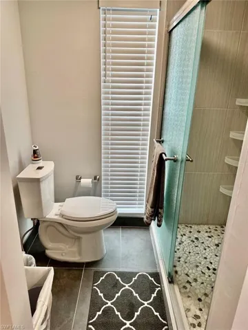 Full bathroom with a shower stall, tile patterned flooring, and toilet