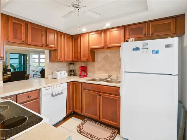 Kitchen with a sink, decorative backsplash, white appliances, and ceiling fan
