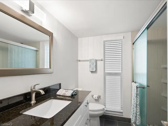remodeled guest bathroom with toilet, a stall shower, vanity, and tile patterned flooring