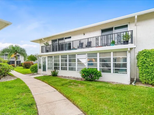 Back of house featuring a yard, a sunroom and a balcony