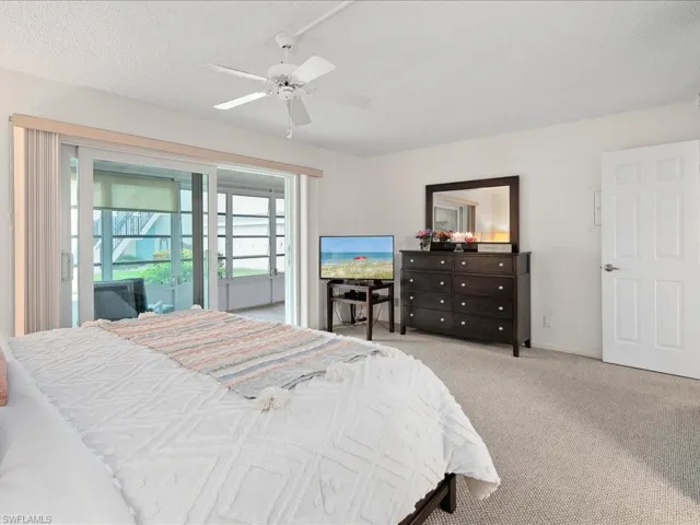 Carpeted bedroom featuring access to exterior, a ceiling fan
