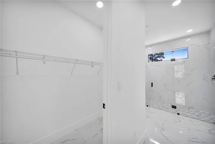 Full bath featuring a walk in closet, a marble finish shower, recessed lighting, and marble finish flooring