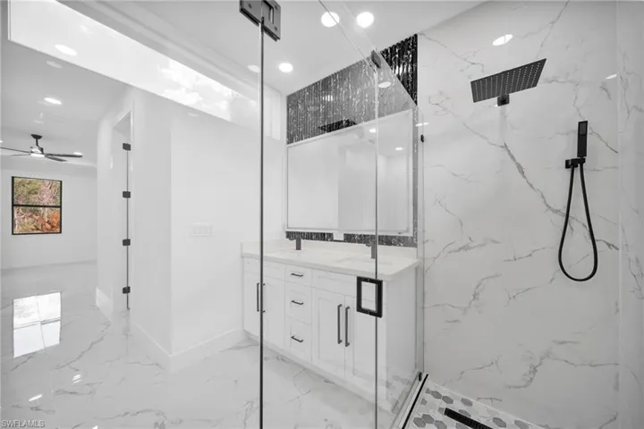 Bathroom with double vanity, a marble finish shower, light marble finish flooring, ceiling fan, and recessed lighting