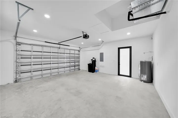 Garage with recessed lighting, electric panel, and water heater