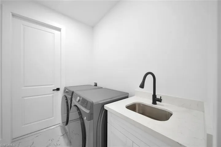 Laundry area with washing machine and dryer and marble look tiles