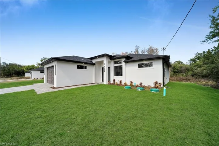 Prairie-style house featuring a front yard, stucco siding, driveway, and an attached garage