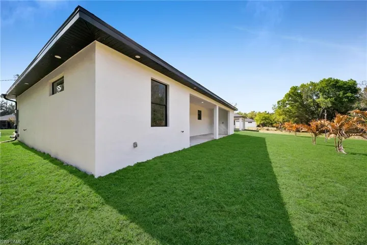 Rear view of house with a yard, stucco siding, and a patio area