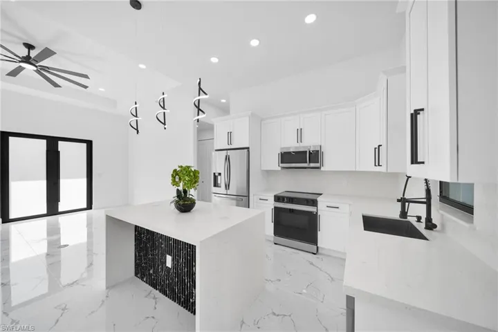 Kitchen featuring stainless steel appliances, pendant lighting, light stone counters, white cabinetry, and ceiling fan