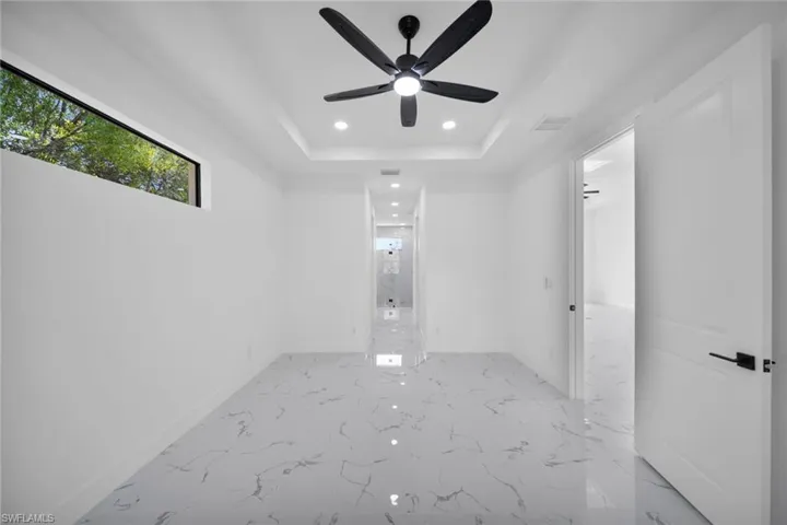 Unfurnished room with recessed lighting, ceiling fan, light marble finish flooring, and a raised ceiling